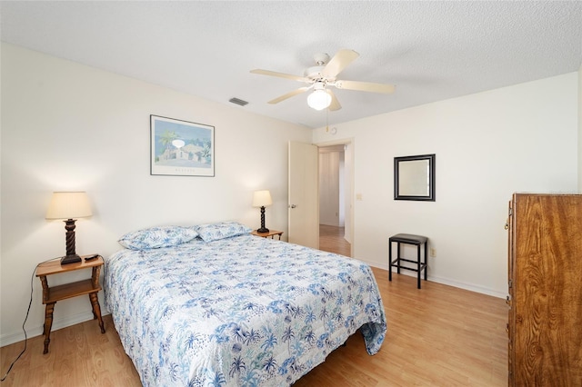 bedroom with a textured ceiling, light hardwood / wood-style flooring, and ceiling fan