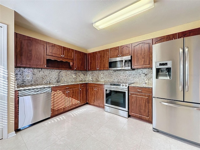 kitchen featuring appliances with stainless steel finishes, backsplash, light stone counters, sink, and light tile patterned floors