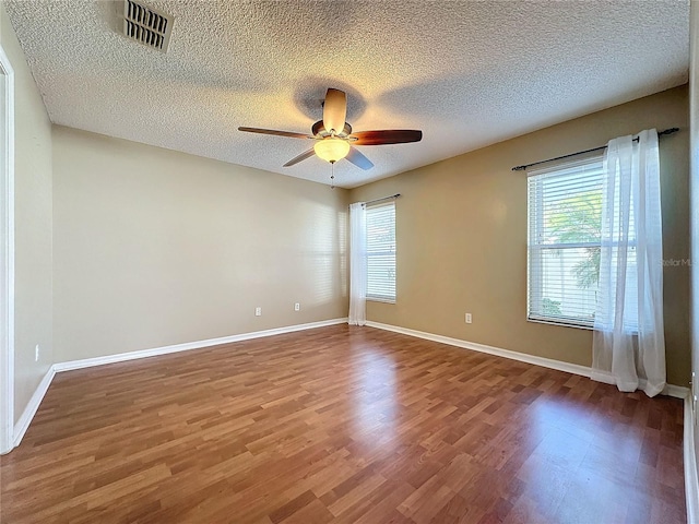 unfurnished room with hardwood / wood-style floors, a textured ceiling, and a wealth of natural light