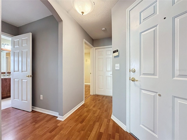 corridor with a textured ceiling and light wood-type flooring