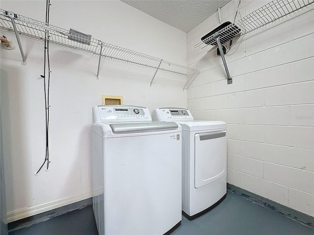 laundry room featuring a textured ceiling and washing machine and clothes dryer