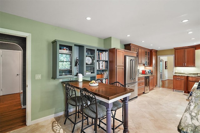 kitchen with light hardwood / wood-style floors, light stone countertops, and high end refrigerator