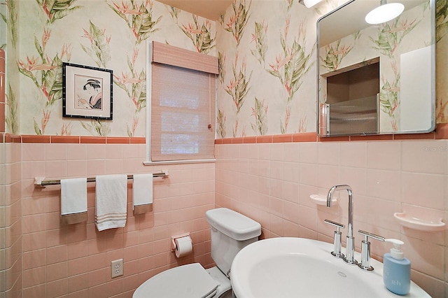 bathroom featuring sink, tile walls, and toilet