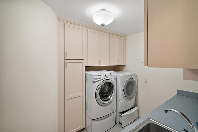 clothes washing area featuring separate washer and dryer, sink, and cabinets