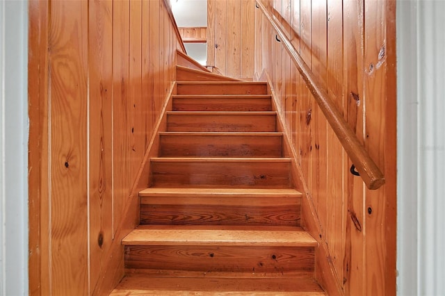 stairway featuring wood walls