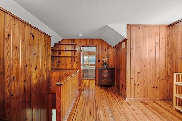 interior space featuring light wood-type flooring, lofted ceiling, and wood walls