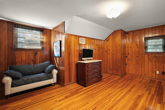 office featuring wood walls, light hardwood / wood-style floors, and vaulted ceiling