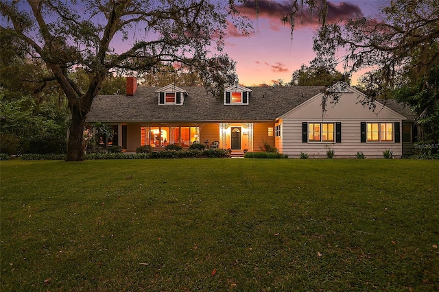 cape cod home with a lawn