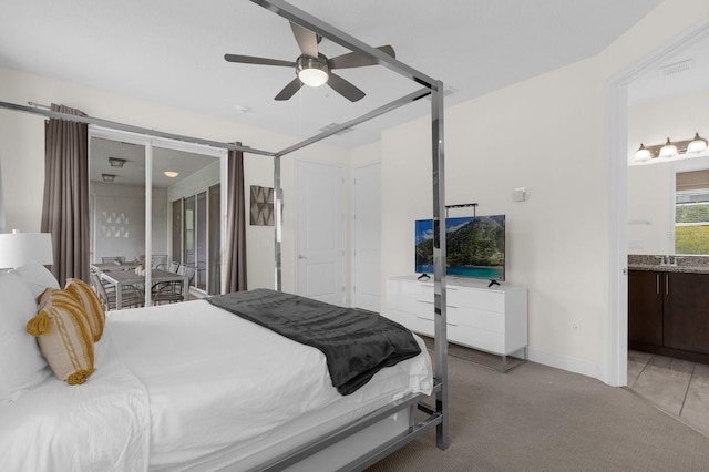 carpeted bedroom with ensuite bathroom and ceiling fan