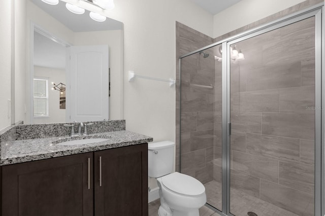 bathroom with an enclosed shower, vanity, and toilet