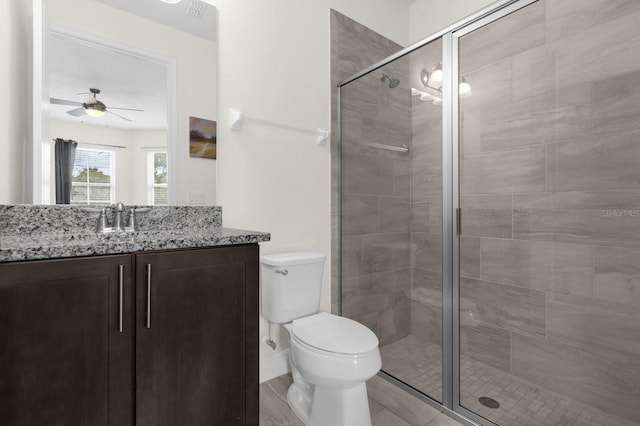 bathroom with ceiling fan, vanity, an enclosed shower, and toilet