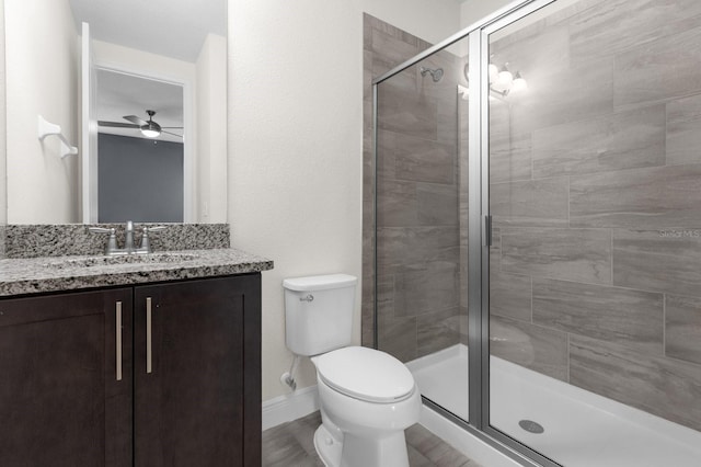 bathroom featuring vanity, ceiling fan, toilet, and a shower with shower door