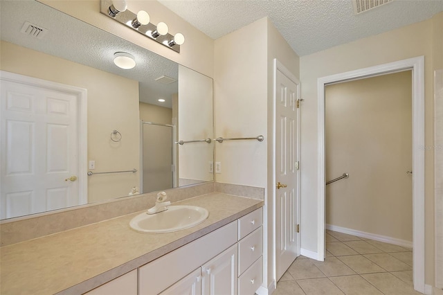 bathroom with tile patterned flooring, vanity, a textured ceiling, and walk in shower