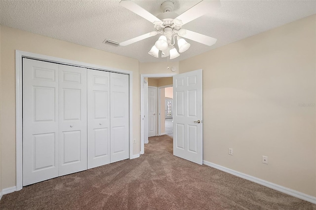 unfurnished bedroom with carpet flooring, ceiling fan, a textured ceiling, and a closet