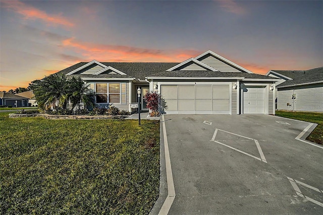 single story home featuring a garage and a lawn