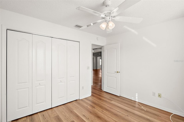 unfurnished bedroom featuring ceiling fan, light wood-type flooring, a textured ceiling, and a closet