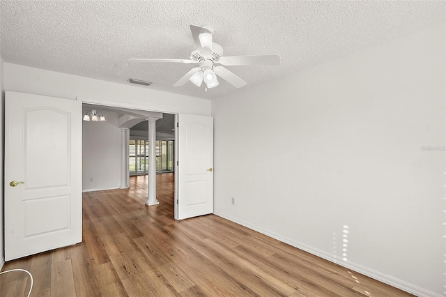 unfurnished room featuring ceiling fan with notable chandelier, light hardwood / wood-style floors, and a textured ceiling