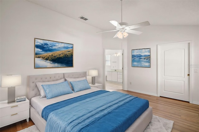 bedroom with ceiling fan, lofted ceiling, ensuite bathroom, and light hardwood / wood-style flooring