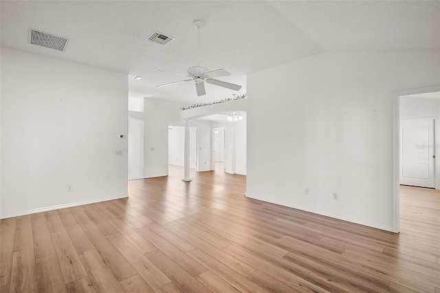 empty room featuring ceiling fan, decorative columns, light hardwood / wood-style floors, lofted ceiling, and a textured ceiling