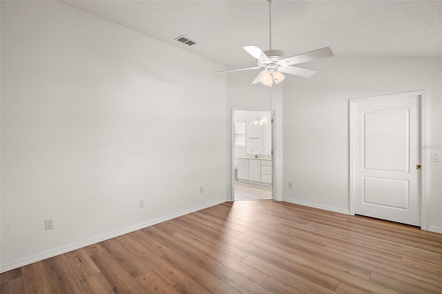 unfurnished room featuring lofted ceiling, ceiling fan, light wood-type flooring, and a textured ceiling