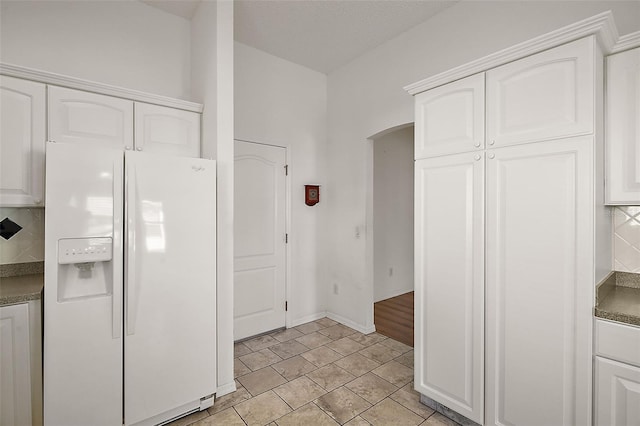 kitchen with white cabinets, tasteful backsplash, and white fridge with ice dispenser