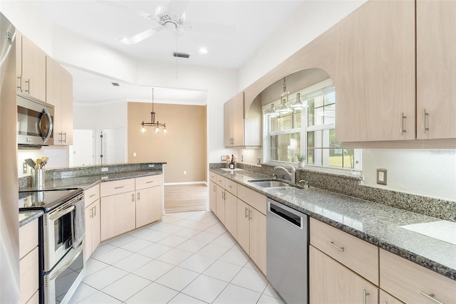 kitchen featuring stainless steel appliances, decorative light fixtures, sink, and light brown cabinets