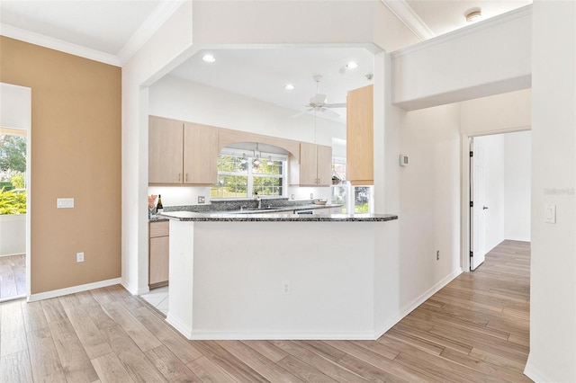 kitchen featuring light hardwood / wood-style flooring, kitchen peninsula, light brown cabinets, and dark stone counters