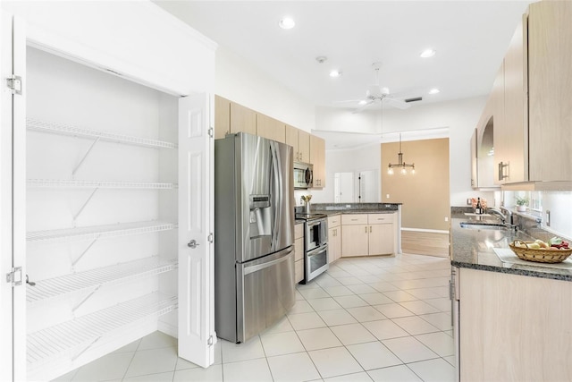 kitchen with appliances with stainless steel finishes, pendant lighting, light brown cabinetry, sink, and ceiling fan