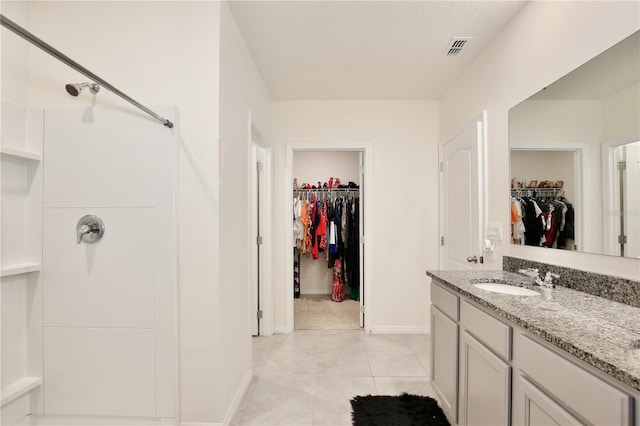 bathroom featuring tile patterned floors, a shower, and vanity