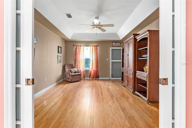 unfurnished room featuring a tray ceiling, light hardwood / wood-style flooring, and ceiling fan