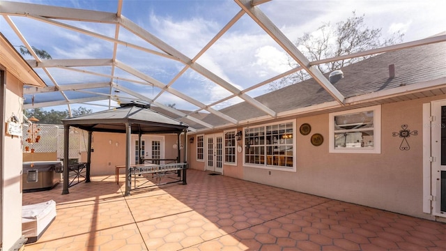 view of patio / terrace with a lanai, french doors, and a hot tub