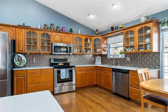 kitchen with tasteful backsplash, stainless steel appliances, vaulted ceiling, sink, and dark hardwood / wood-style floors