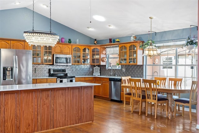 kitchen featuring pendant lighting, stainless steel appliances, vaulted ceiling, and hardwood / wood-style flooring