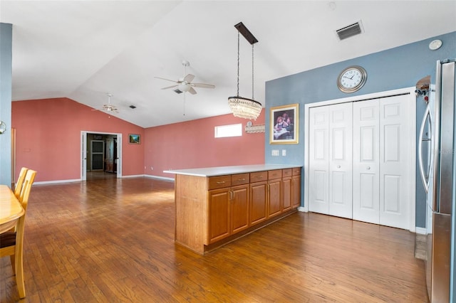 kitchen featuring stainless steel refrigerator, lofted ceiling, kitchen peninsula, and decorative light fixtures