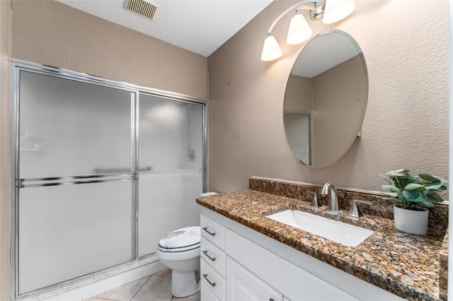 bathroom featuring toilet, vanity, tile patterned floors, and an enclosed shower