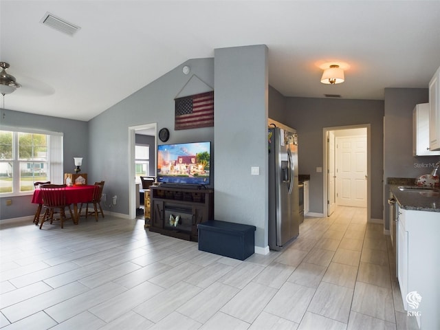 living room featuring ceiling fan, sink, and lofted ceiling