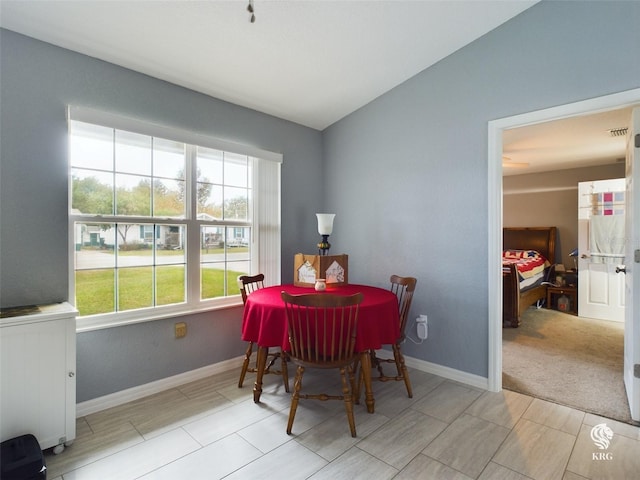 dining space with plenty of natural light, light carpet, and vaulted ceiling