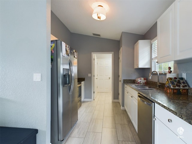 kitchen with white cabinetry, appliances with stainless steel finishes, light tile patterned floors, sink, and lofted ceiling