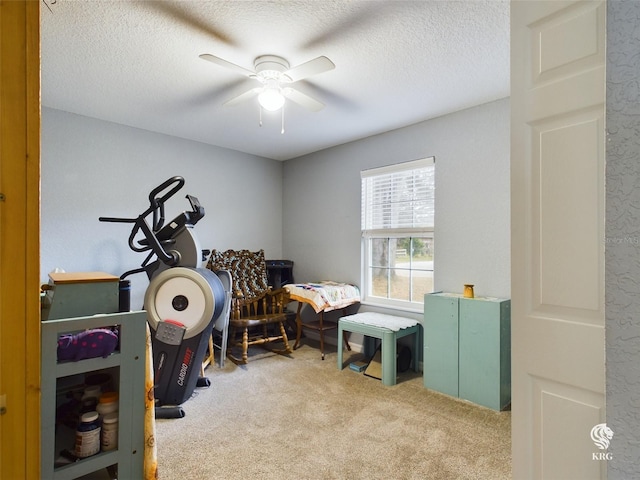 interior space with a textured ceiling, light carpet, and ceiling fan