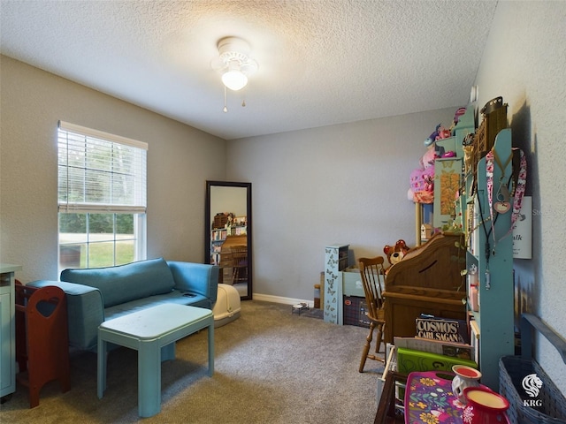 living area with carpet, a textured ceiling, and ceiling fan