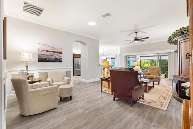 living room with ceiling fan, crown molding, and light hardwood / wood-style flooring