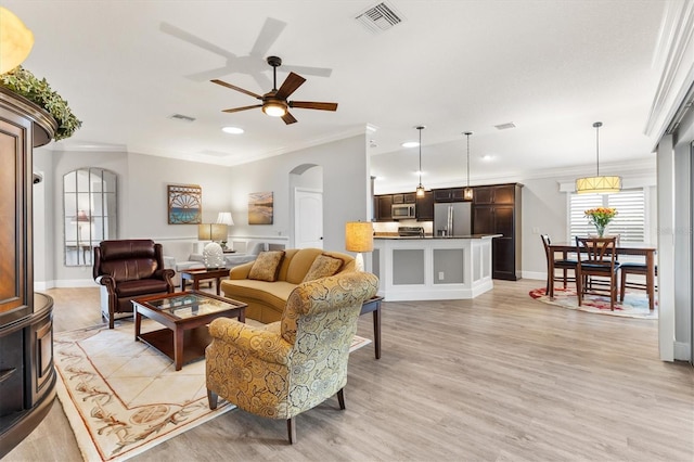 living room featuring ceiling fan, ornamental molding, and light hardwood / wood-style flooring