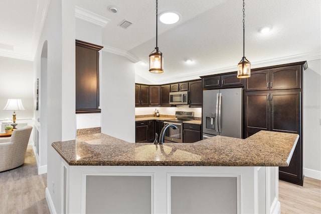 kitchen with appliances with stainless steel finishes, light wood-type flooring, hanging light fixtures, and ornamental molding