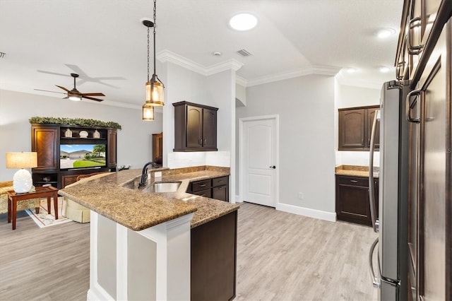 kitchen with light wood-type flooring, light stone counters, crown molding, sink, and stainless steel refrigerator