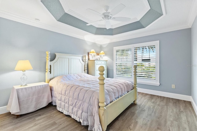 bedroom featuring hardwood / wood-style floors, a raised ceiling, ceiling fan, and crown molding