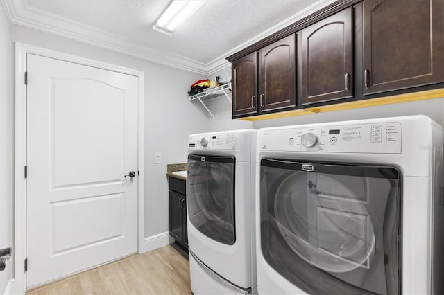 laundry room with washing machine and clothes dryer, cabinets, light hardwood / wood-style floors, a textured ceiling, and ornamental molding