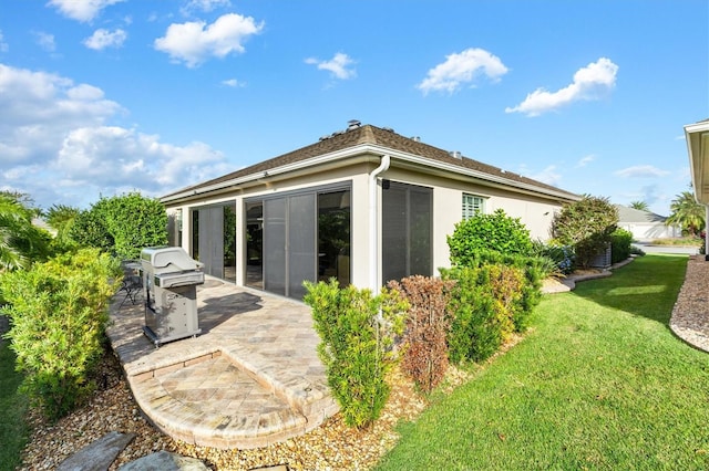 rear view of house featuring a lawn and a patio