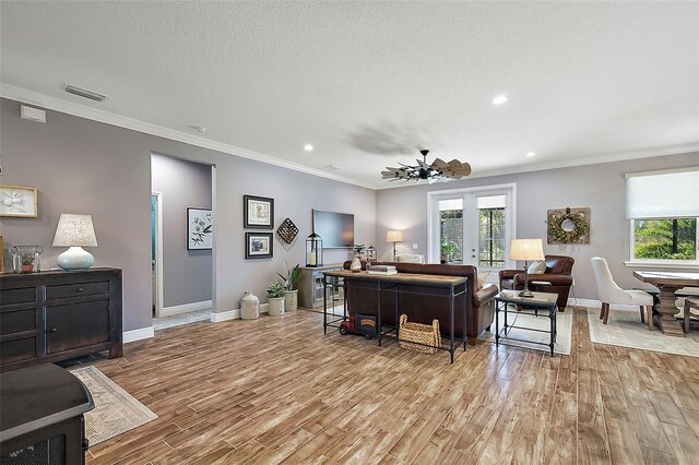 living room with a textured ceiling, light hardwood / wood-style flooring, ceiling fan, and ornamental molding