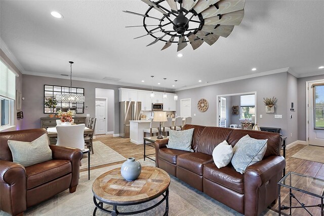 living room with crown molding, light hardwood / wood-style flooring, and ceiling fan