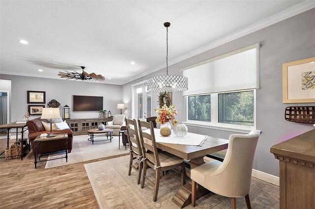 dining area with plenty of natural light, wood-type flooring, ornamental molding, and ceiling fan with notable chandelier